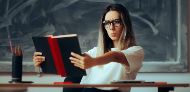 Mulher com presbiopia a afastar um livro para conseguir ler