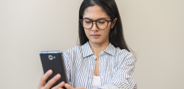 Mulher a afastar o telemóvel para ver com clareza.