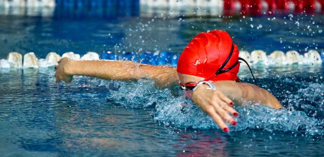 Rapariga a nadar com óculos de natação numa piscina.