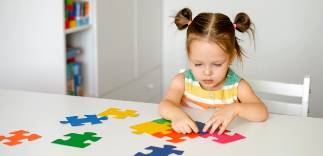 Menina a fazer um puzzle com peças coloridas.