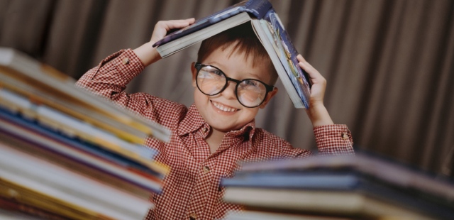 Criança com óculos rodeada de livros